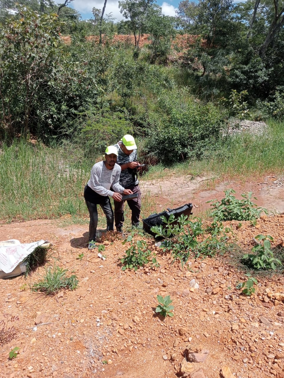 Two NECTAR surveyors in hi-vis caps setting up instruments beside a working pit