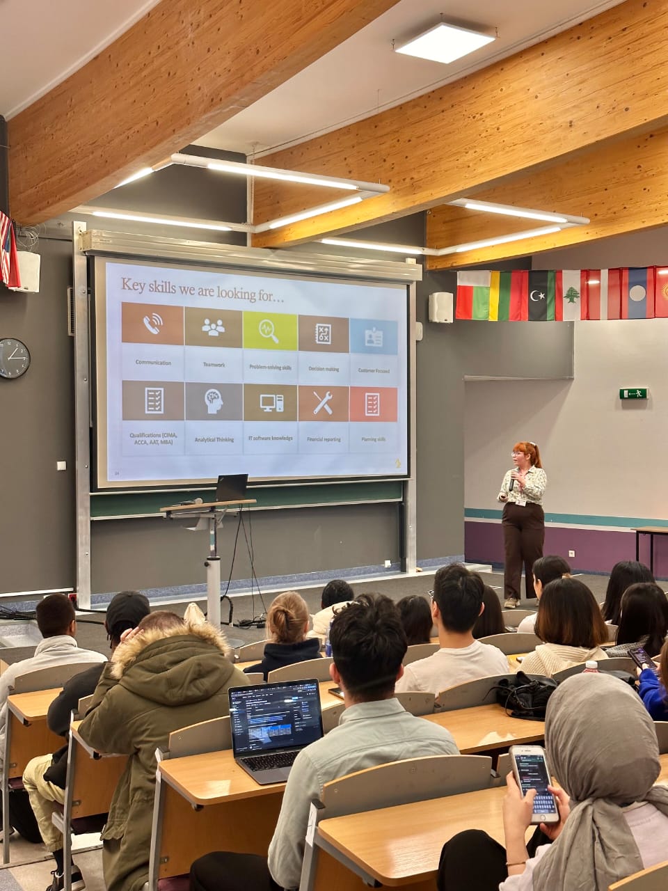 A careers lecture in a full auditorium at Vistula University, with international flags along the wall
